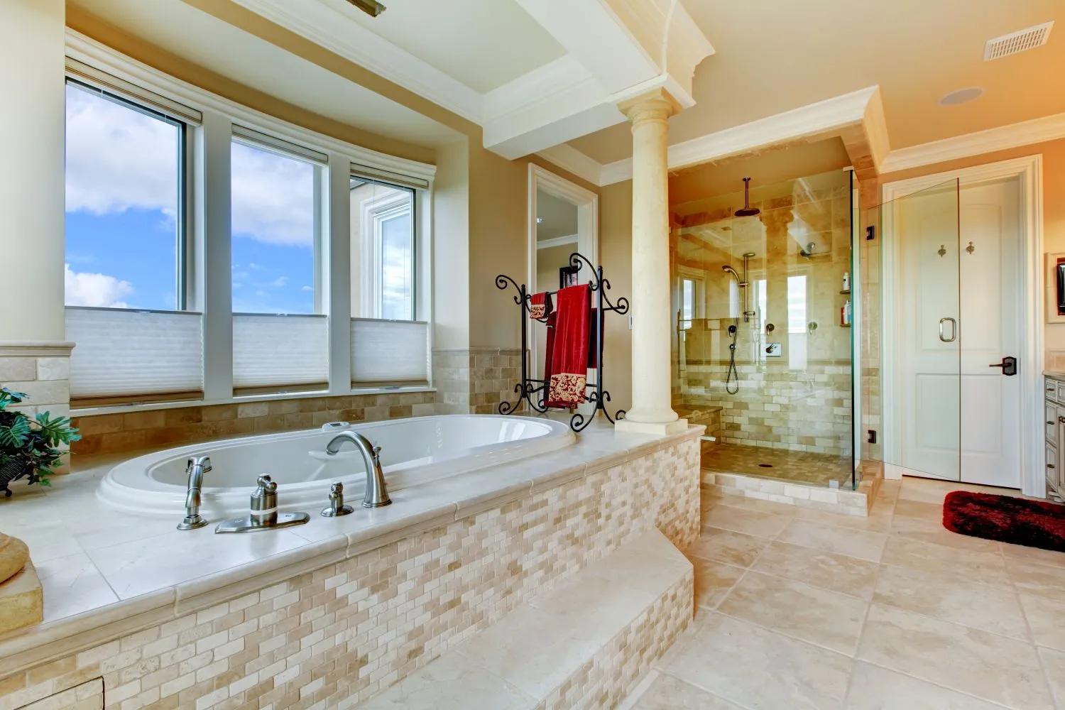 An elegant bathroom remodel featuring a soaking tub, glass-enclosed shower, and marble tile flooring
